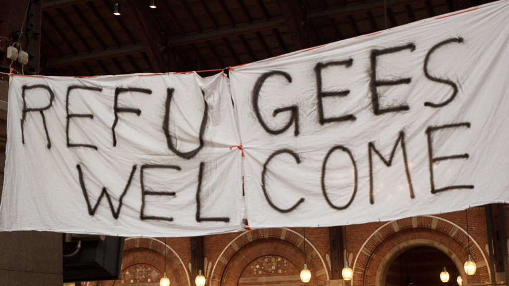 Handmade banner Refugees Welcome is hanged in Copenhagen railroad station by the place where locals bring clothes for refugees.